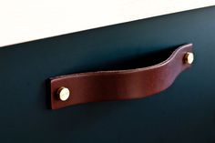 a brown leather drawer handle on a black cabinet