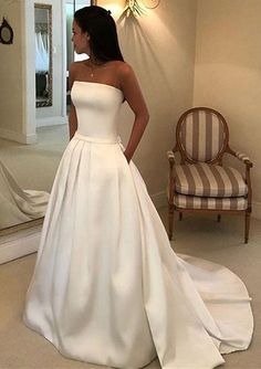 a woman standing in front of a mirror wearing a wedding dress