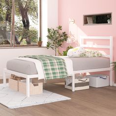 a white bed sitting on top of a hard wood floor next to a pink wall