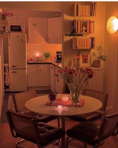 a kitchen with a table, chairs and refrigerator in the background is lit by candles