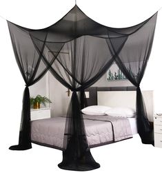 a black canopy bed with white sheets and pillows