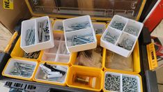 there are many different types of screws in the box and on the table,