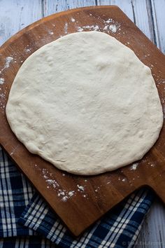 a wooden cutting board topped with dough on top of a table