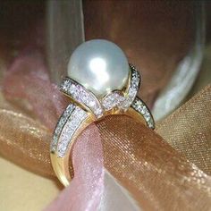 a close up of a ring with a pearl and diamonds on it's side