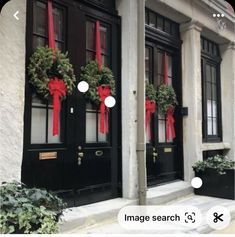 two black doors with red bows and wreaths on the front, and another door is decorated with greenery