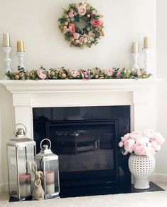 a fireplace decorated with pink flowers and candles next to a wreath on top of the mantle