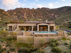 an aerial view of a house in the desert with a pool and mountains behind it