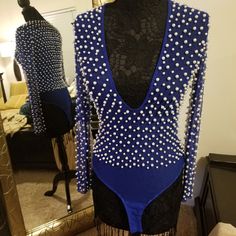 a blue and black leotard with white beads on the back, in front of a mirror