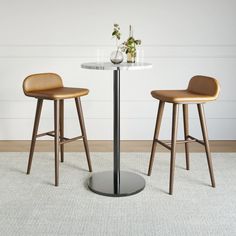 two stools and a table in a room with white walls, flooring and carpet