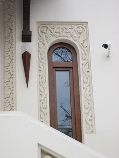 a door and window on the side of a white building with an ornamental design around it