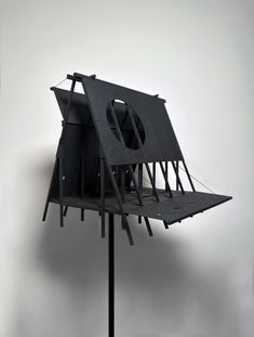 a black object on a metal stand in front of a white wall