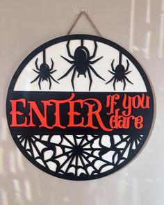 a sign that says enter if you dare hanging from a wall with spider webs on it