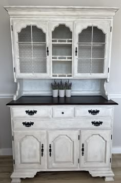 an old white china cabinet with black top