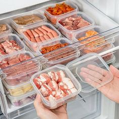 two hands reaching into an open refrigerator door with food in plastic containers on the shelves