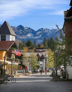 a town with mountains in the background and people walking down the street on either side