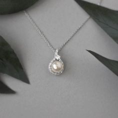 A single ivory pearl is surrounded in a bright wrap of micro pave CZ jewels and a single pear cut stone. This pendant is .75 inches long on a 16-inch chain with a two-inch extender. It is available in rhodium silver, or gold plate and is lead, nickel, and cadmium free, with AAA grade CZ. Matches these earrings. Small Pendants, Cz Necklace, Cz Pendant, Ivory Pearl, Affordable Jewelry, Small Pendant, Wedding Jewelry Sets, Pretty Jewellery, Gold Pendant Necklace