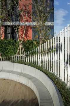 a white picket fence next to a building with a clock on the front and side of it