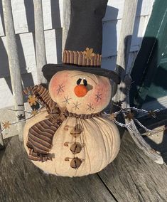 a snowman sitting on top of a wooden bench next to a fence and door