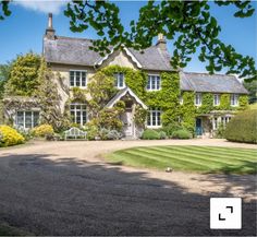 a large house with lots of green plants on the front and side of it's facade