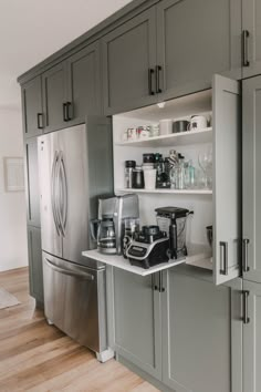 a kitchen with gray cabinets and stainless steel appliances on the counter top, along with an open refrigerator