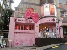 a pink hello kitty cafe on the corner of a street in front of a building