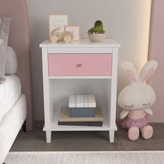 a pink and white nightstand next to a bed with a stuffed bunny on top of it