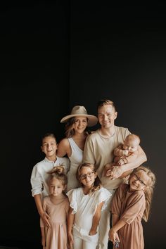 a group of people standing next to each other in front of a black wall with one person holding a baby