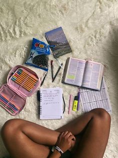 a woman is sitting on the floor with her legs crossed and books, pens, pencils, and other items