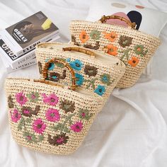 two straw bags sitting on top of a white bed next to a book and magazine