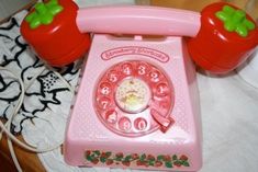 an old fashioned pink phone with two red tomatoes on it