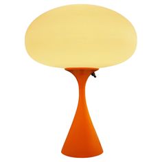 an orange table lamp sitting on top of a white floor