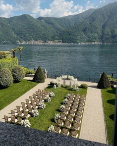 an outdoor ceremony set up with chairs and flowers on the lawn by the water's edge