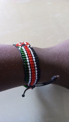 a person's arm with two bracelets on it, one is red white and green