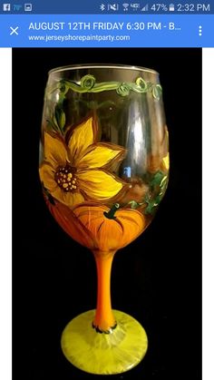 a yellow wine glass with sunflowers painted on the side and green stemings