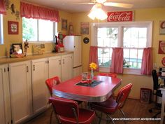 a red table and chairs in a small room with yellow walls, coca - cola sign on the wall