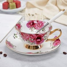 a tea cup and saucer with pink roses on it