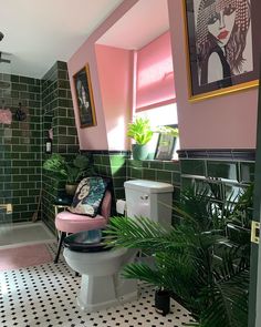 a bathroom with pink walls and black and white flooring, potted plants on the toilet