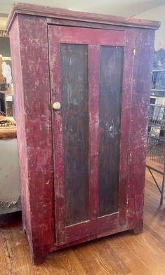 an old red cabinet sitting on top of a hard wood floor