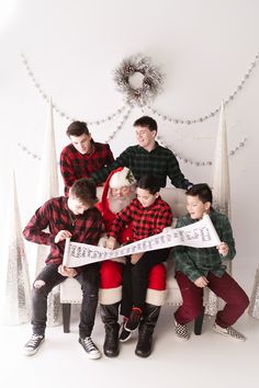 a group of people sitting next to each other in front of a christmas tree holding a sign