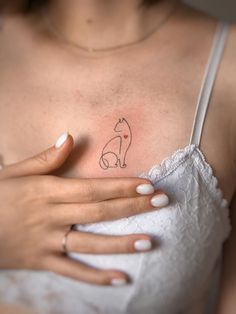 a woman's chest with a small cat tattoo on it