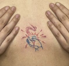 two hands are holding up the chest with a small tattoo on it's left side