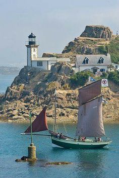 a small sailboat in the water near a lighthouse