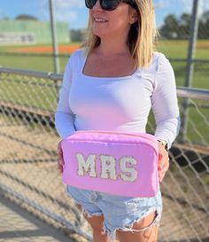 a woman is holding a pink bag with the word mrs on it