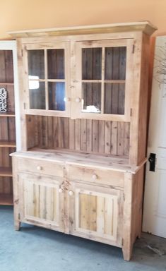 a large wooden cabinet sitting next to a book shelf with glass doors on the top