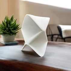 a white sculpture sitting on top of a wooden table next to a potted plant