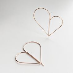 two pairs of heart shaped earrings on a white surface