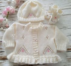 This hand knitted baby girls cardigan with matching hat & boots is the perfect little knitted sweater to keep your little ones warm, it matches perfectly with all your other baby clothes, jeans, leggings dresses.  This knitted outfit also makes a great gift for new moms or to give as a baby shower gift The cute baby sweater is hand knitted in soft acrylic baby yarn with a lovely lacy pattern to front & back the front is also hand embroidered with silk flowers  The Cardigan is finished with delic Cute Winter Knitting Pattern, Cute Winter Sweater As A Gift, Fitted Cream Cute Sweater, Cute Fitted Cream Sweater, Cute Handmade Knitting Pattern For Winter, Handmade Cute Winter Knitting Pattern, Cute Handmade Winter Knitting Pattern, Cute Fitted Knitted Cardigan, White Hand Knitted Fitted Knitting Pattern