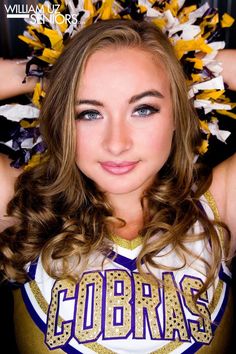 a girl in a cheer uniform with her hands on her head while posing for the camera