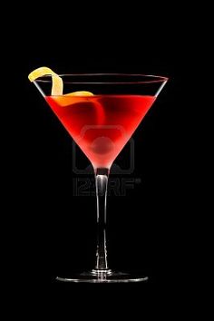 a red cocktail in a martini glass with an orange slice on the rim and black background