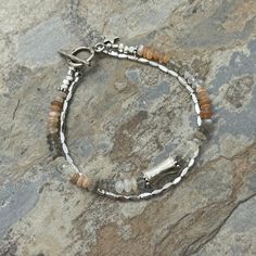 This double stranded bracelet is handmade using natural gemstones and the highest quality Sterling Hill Tribe silver. One strand is multi colored moonstone rondelles and a large Hill Tribe silver bead at the center. The other strand is Hill Tribe liquid silver, each separated with tiny silver beads. Finished with a silver Hill Tribe toggle clasp and star charm. Multi moonstone: 4mm Sterling silver center bead: 12 x 7mm Sterling silver toggle: 12mm Your jewelry will arrive in a cotton lined kraft box within a padded postal envelope. I use USPS first class mail. This usually takes 3 to 5 days to ship. International orders outside of the U.S. will take 8 to 15 days to ship. To see more from East Village Jewelry~ http://eastvillagejewelry.etsy.com All orders ship out within 24 hours, excluding Silver Rondelle Gemstone Beaded Bracelets, Silver Gemstone Bead Rondelle Bracelets, Silver Rondelle Bracelets With Natural Stones, Silver Rondelle Bracelets With Gemstone Beads, Silver Double Strand Beaded Bracelets With Gemstones, Silver Double Strand Bracelets With Gemstone Beads, Silver Double Strand Bracelet With Natural Stones, Silver Bracelets With Natural Stones And Round Beads, Silver Beaded Bracelets With Natural Stones